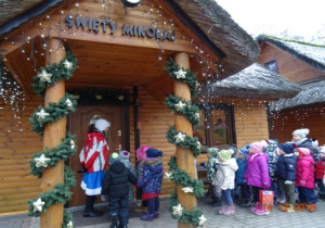 Dzieci stoją przed domkiem Świętego Mikołaja.